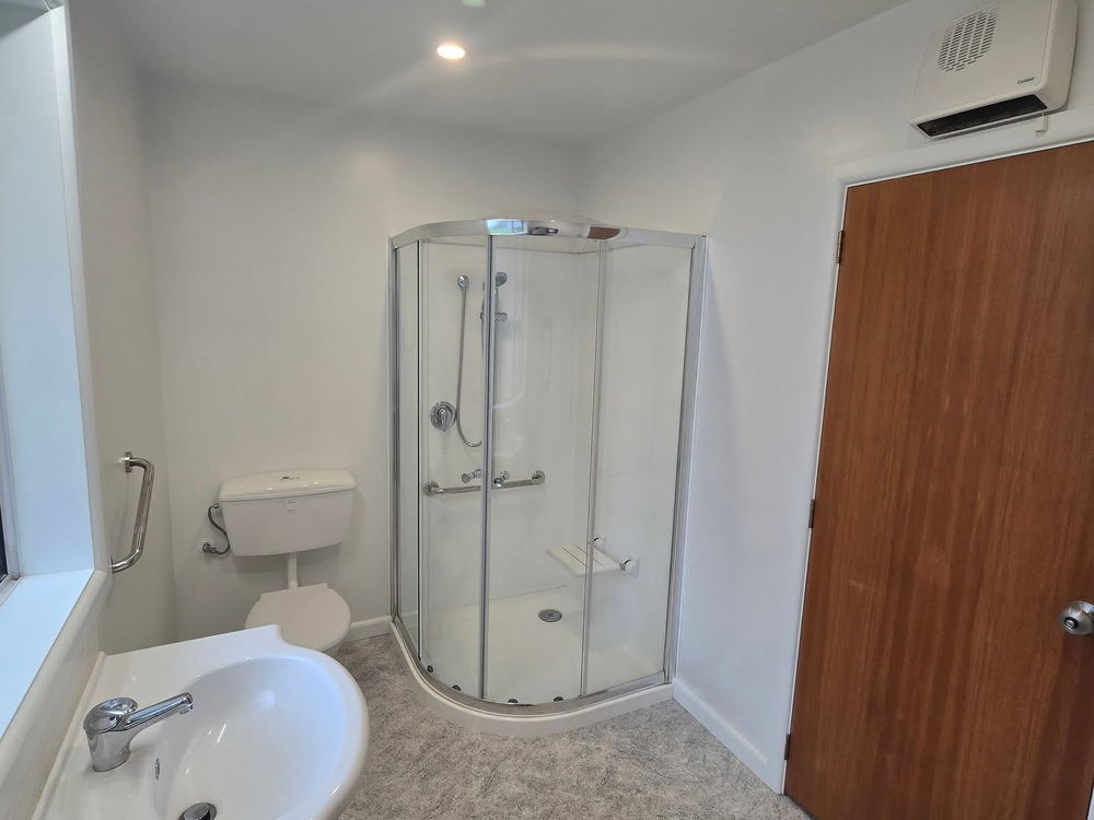 Finished bathroom with a corner shower, a white vanity and a vinyl plank floor