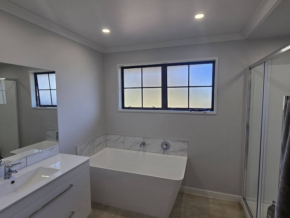 Freestanding bath and glass shower in a newly renovated white bathroom
