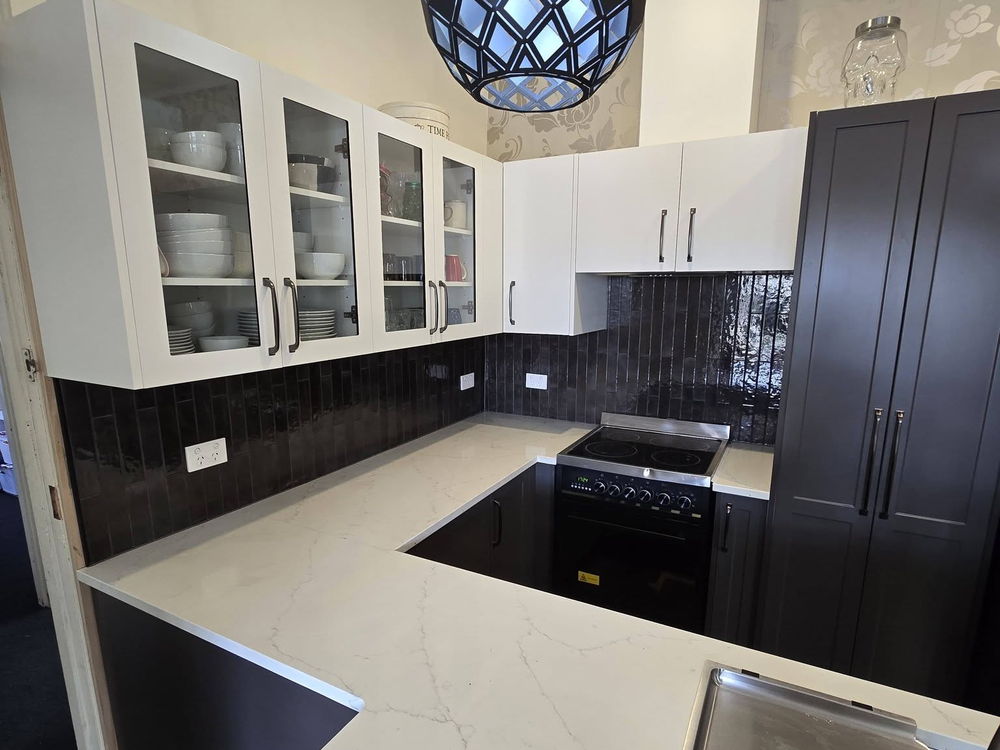Renovated kitchen with a stone benchtop, dark cabinets and a patterned pendant light