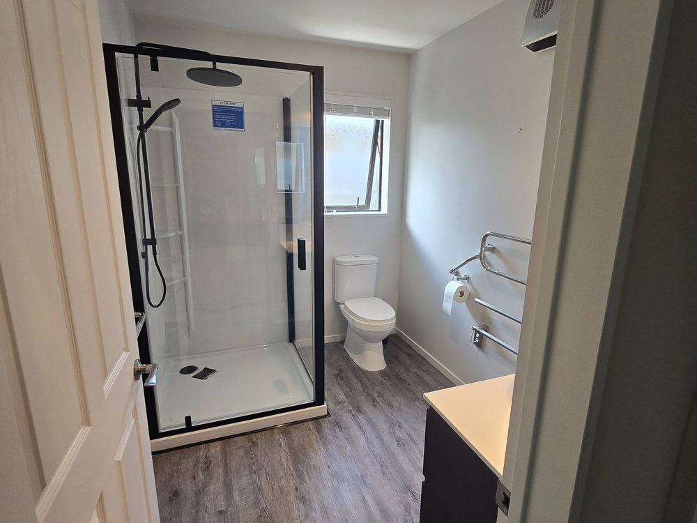 Black-framed glass shower and heated towel rail in a finished bathroom