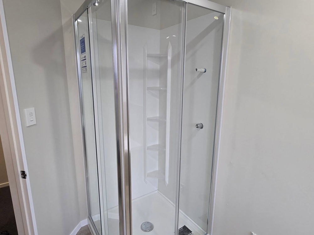 Corner shower with a chrome frame on a vinyl plank floor