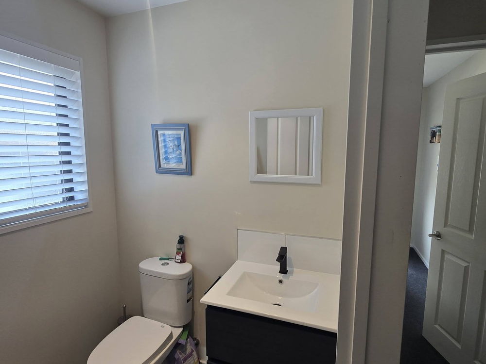 Black wall-hung vanity, toilet and a window with a blind in a renovated bathroom
