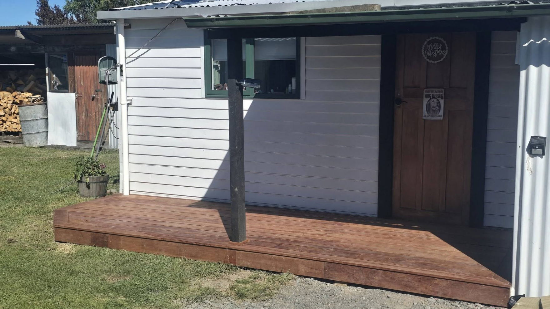 Stained timber veranda deck and post on the front of a weatherboard cottage with a corrugated iron roof